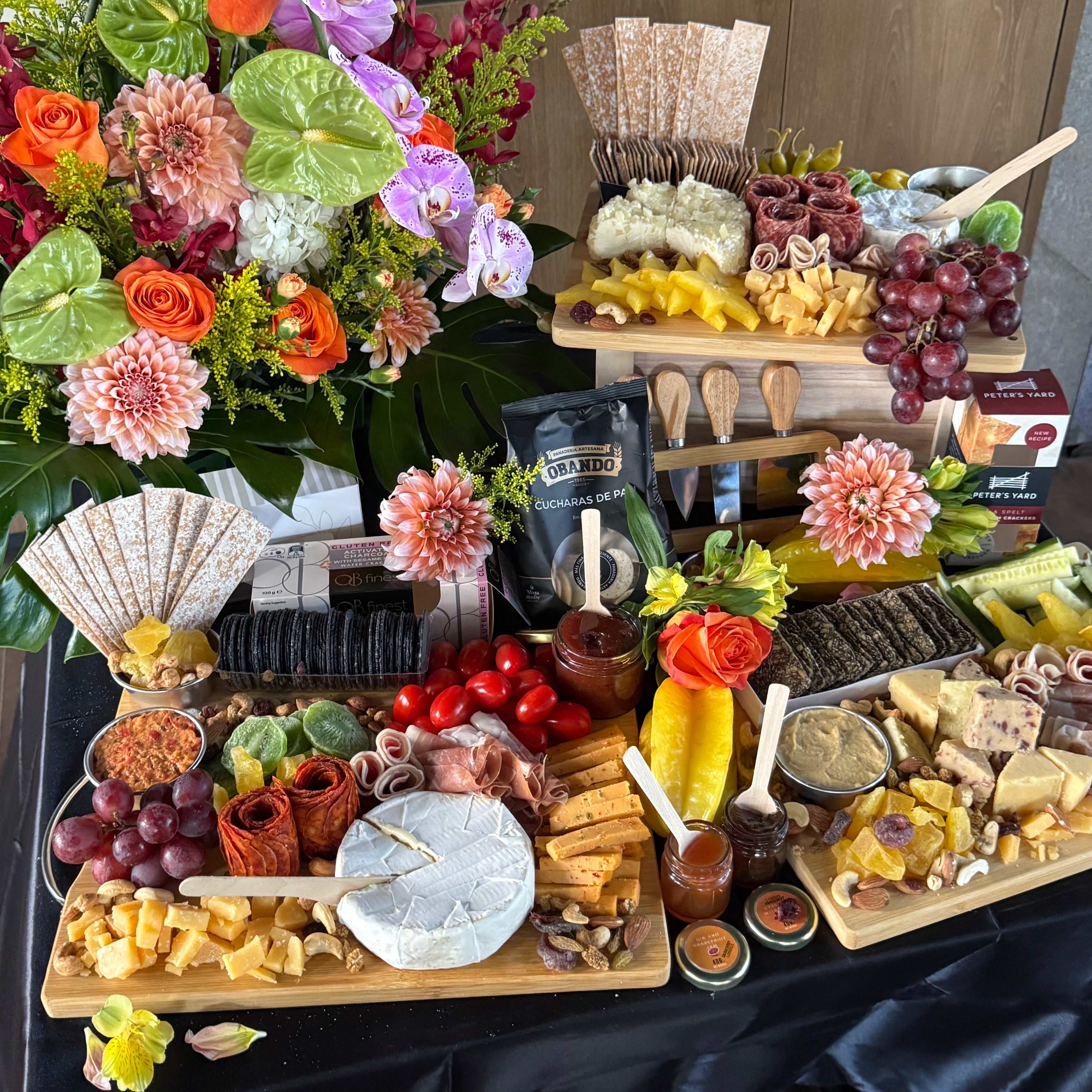 Cheese and charcuterie grazing table set up for a corporate event, with flowers and boards — The Cheese Board Singapore